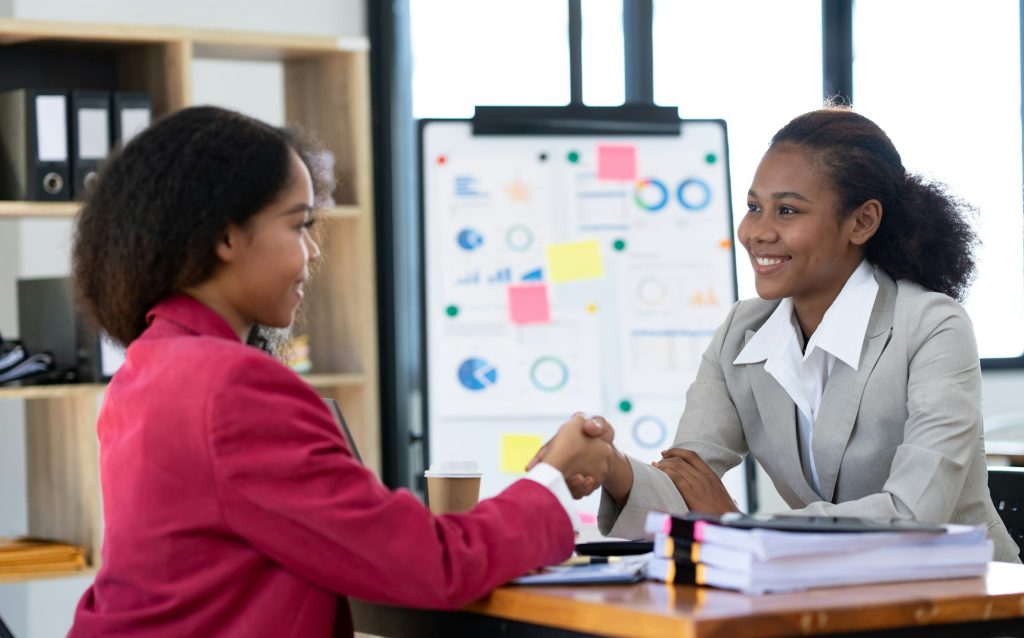 Two young African businesswomen are sitting and talking. Consulting business information showing res
